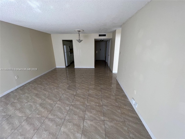 unfurnished room featuring tile flooring and a textured ceiling