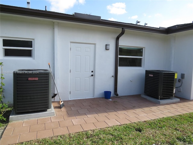 view of exterior entry featuring central AC unit and a patio