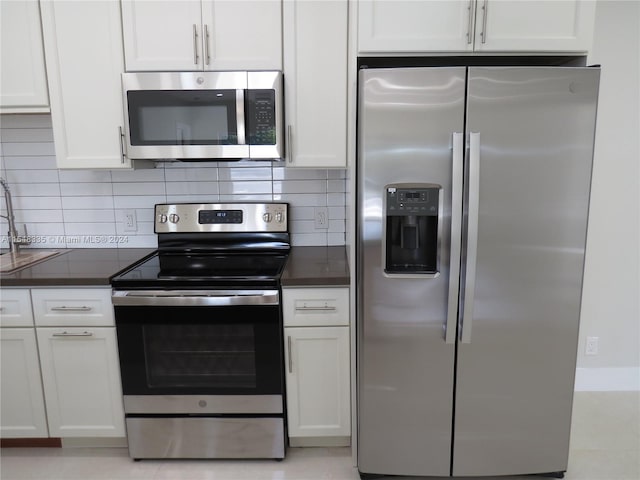 kitchen with tasteful backsplash, stainless steel appliances, light tile flooring, and white cabinets