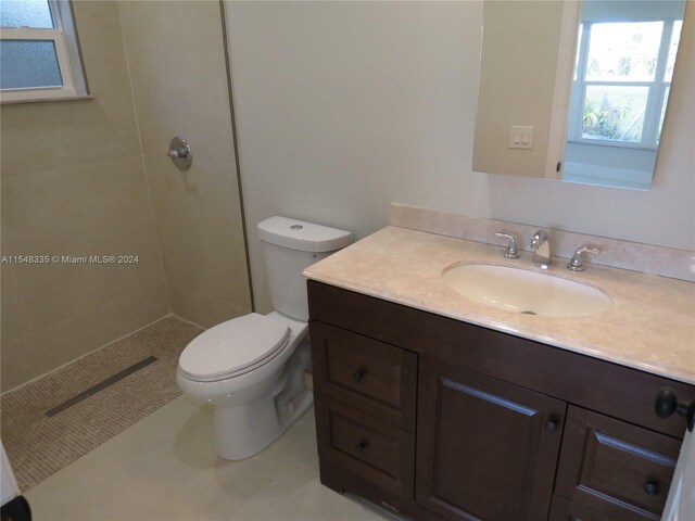 bathroom featuring oversized vanity, toilet, and a tile shower