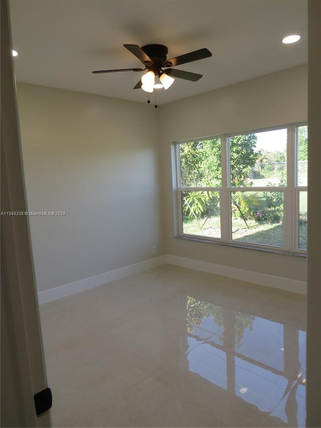 tiled empty room featuring ceiling fan