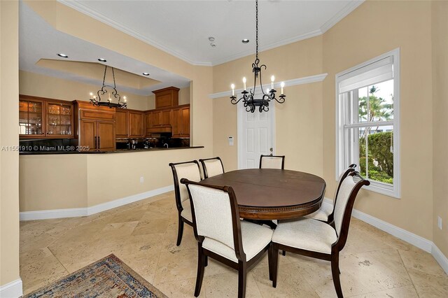 dining space featuring a tray ceiling, a chandelier, and ornamental molding