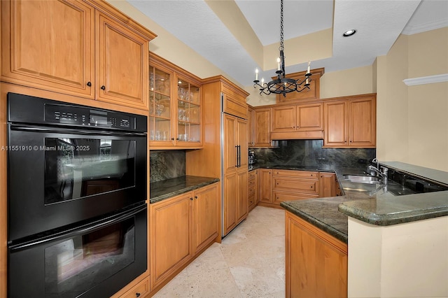 kitchen with sink, a notable chandelier, backsplash, kitchen peninsula, and black double oven