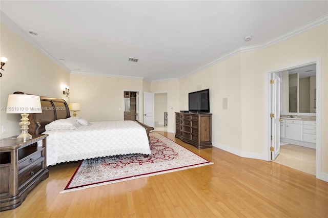 bedroom featuring ensuite bathroom, ornamental molding, and hardwood / wood-style flooring