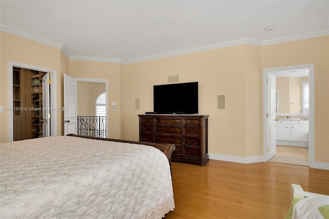 bedroom with ensuite bath, ornamental molding, hardwood / wood-style flooring, a spacious closet, and a closet