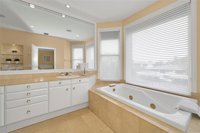 bathroom with tile patterned flooring, vanity, and tiled tub