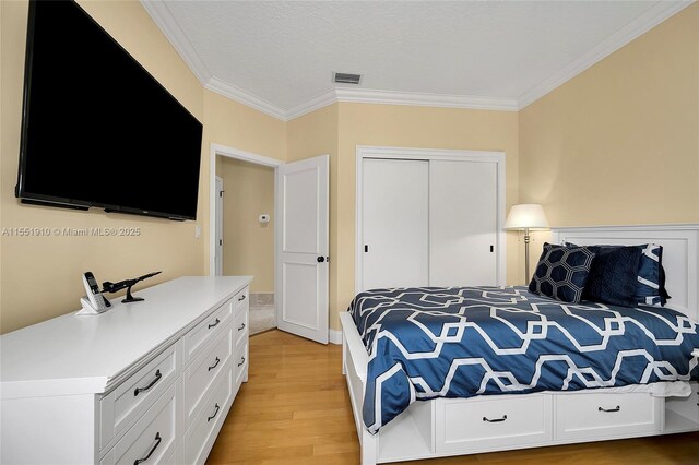 bedroom with light hardwood / wood-style flooring, a closet, and crown molding