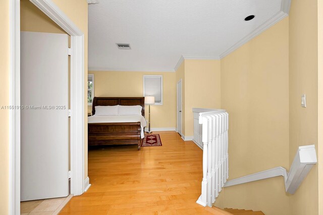 corridor with light wood-type flooring and crown molding