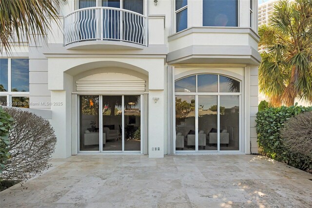 view of exterior entry featuring a balcony and a patio