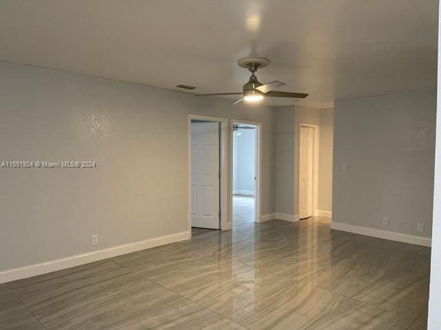 spare room with dark tile flooring and ceiling fan