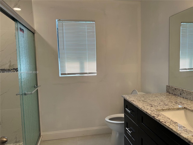 bathroom featuring an enclosed shower, tile flooring, vanity with extensive cabinet space, and toilet