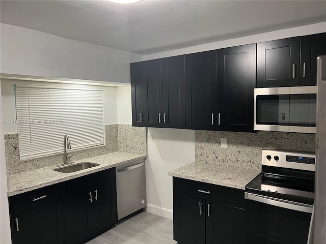 kitchen with backsplash, stainless steel appliances, sink, and light stone counters