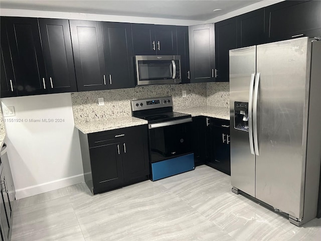 kitchen featuring light stone countertops, tasteful backsplash, stainless steel appliances, and light tile floors