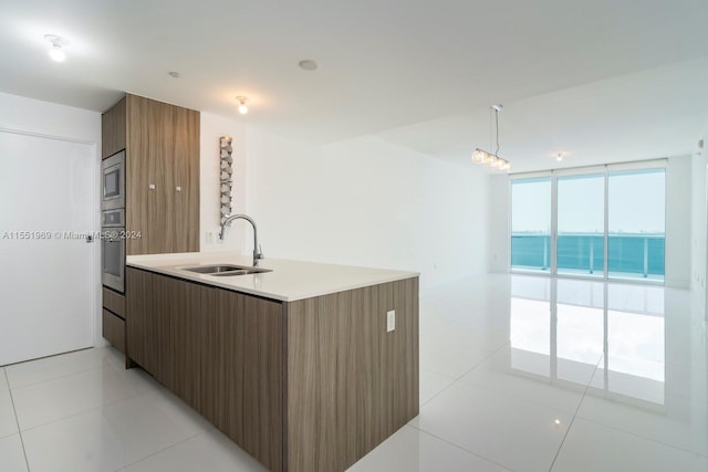 kitchen featuring stainless steel appliances, pendant lighting, floor to ceiling windows, sink, and light tile flooring