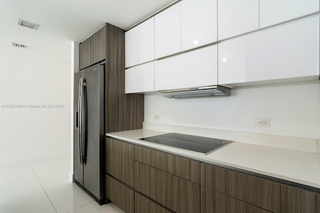 kitchen with black electric cooktop, white cabinetry, stainless steel fridge, light tile floors, and range hood