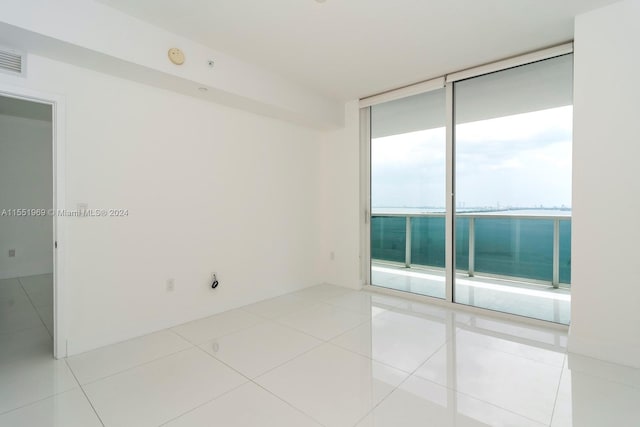 tiled spare room featuring a wall of windows