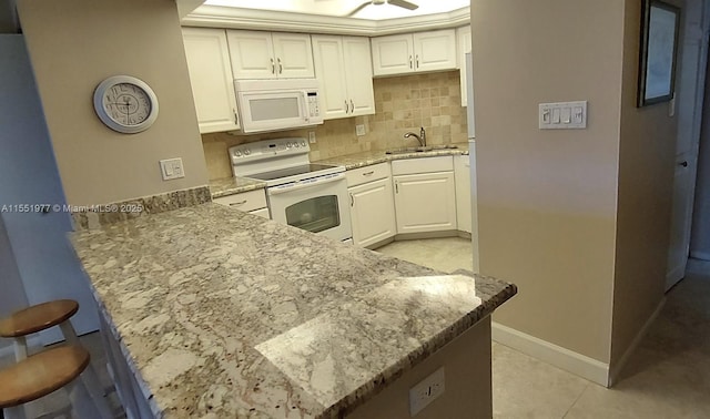 kitchen with sink, kitchen peninsula, white appliances, decorative backsplash, and white cabinets