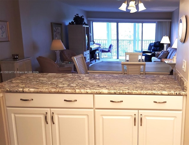 kitchen featuring light stone countertops, plenty of natural light, and white cabinets