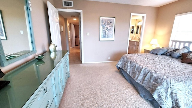 bedroom featuring light colored carpet and ensuite bath