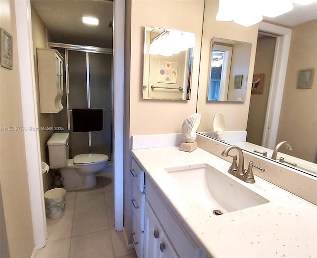 bathroom featuring vanity, a shower with door, tile patterned floors, and toilet