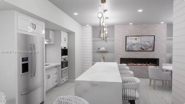 kitchen with white cabinetry, appliances with stainless steel finishes, decorative light fixtures, and a stone fireplace