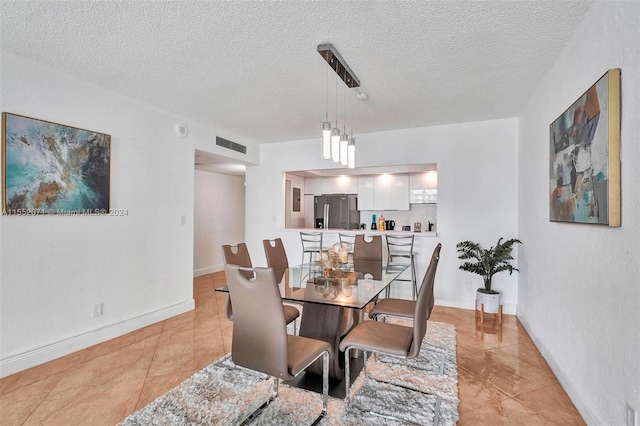 tiled dining space with a textured ceiling