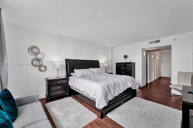 bedroom with a textured ceiling and dark hardwood / wood-style floors