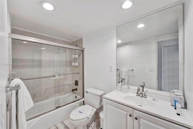 full bathroom with enclosed tub / shower combo, toilet, large vanity, and tile flooring