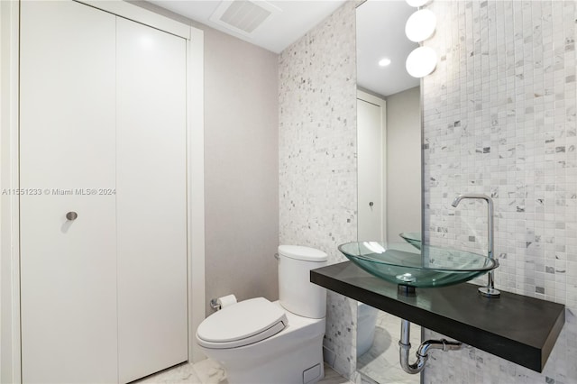 bathroom featuring toilet, tile floors, and tile walls