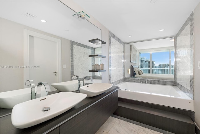 bathroom with double sink, tile flooring, vanity with extensive cabinet space, and tiled bath