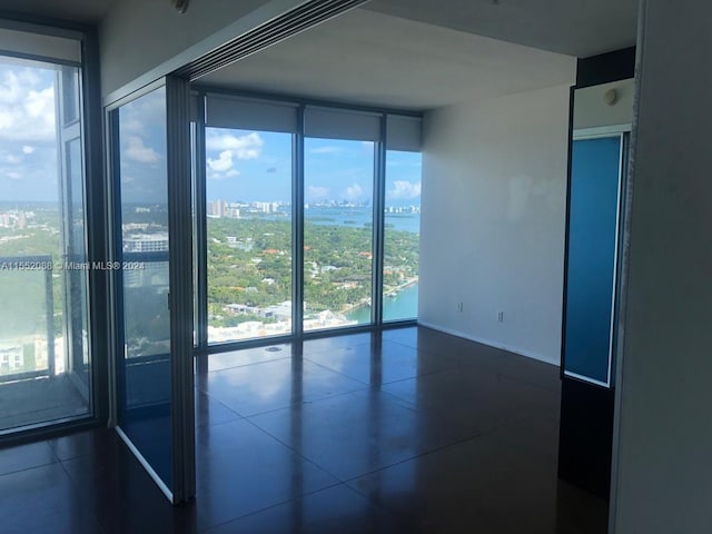 spare room featuring floor to ceiling windows and dark tile flooring