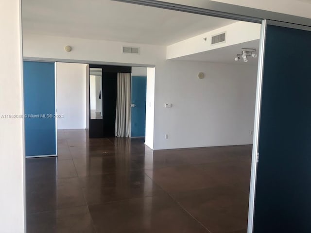 unfurnished room featuring dark tile flooring and a notable chandelier