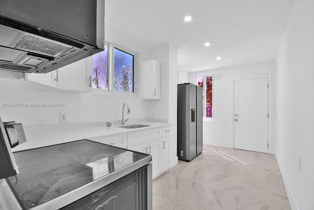 kitchen featuring stainless steel fridge, sink, light tile floors, island range hood, and white cabinetry