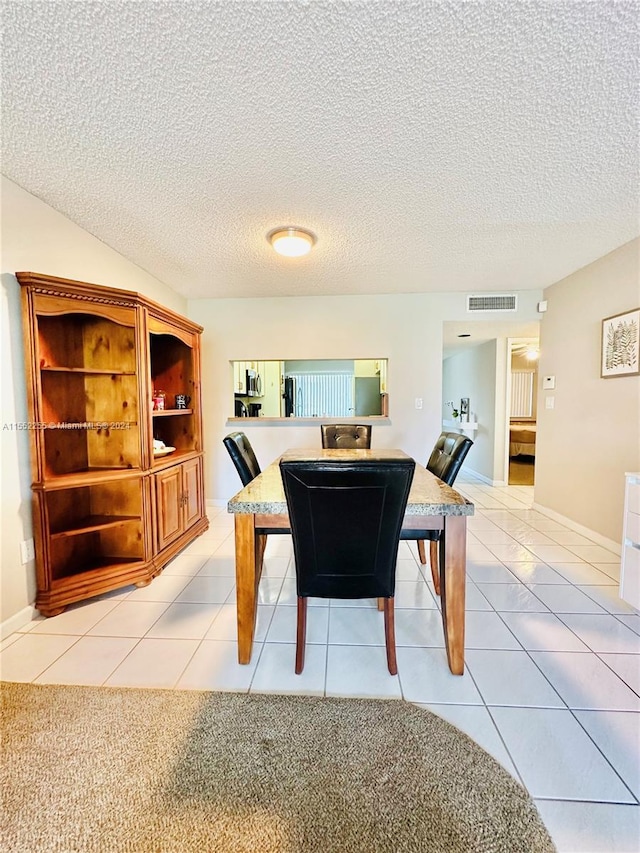 dining area with light tile patterned floors and a textured ceiling