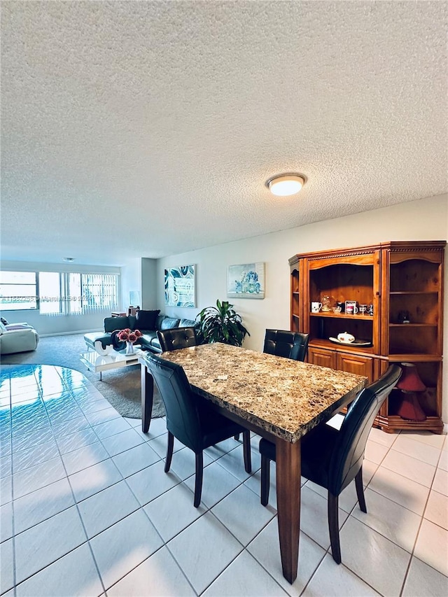 dining space featuring light tile patterned flooring and a textured ceiling