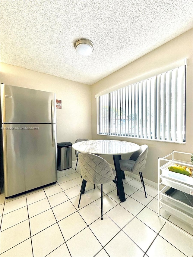 dining area featuring light tile patterned floors and a textured ceiling