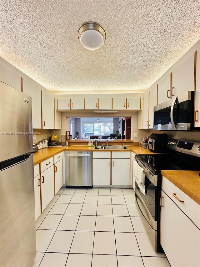 kitchen featuring a textured ceiling, light tile patterned flooring, sink, and appliances with stainless steel finishes