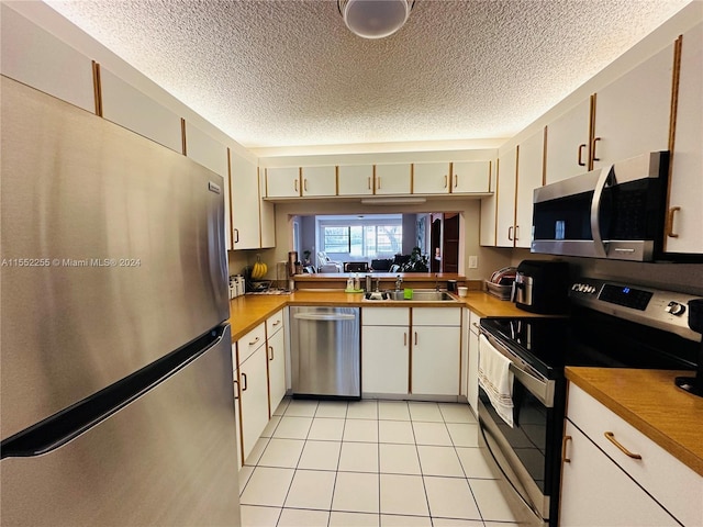 kitchen with light tile patterned floors, a textured ceiling, stainless steel appliances, and sink