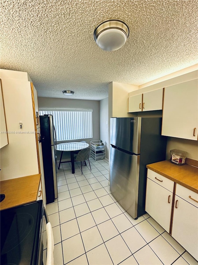 kitchen with butcher block countertops, stainless steel fridge, and white cabinets