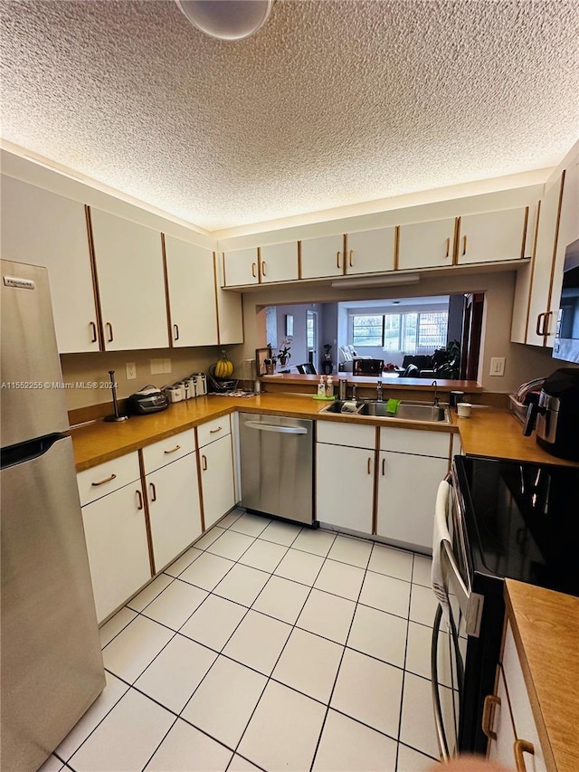 kitchen with sink, light tile patterned floors, a textured ceiling, and appliances with stainless steel finishes