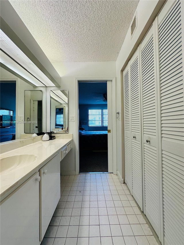 bathroom with a textured ceiling, vanity, and tile patterned floors