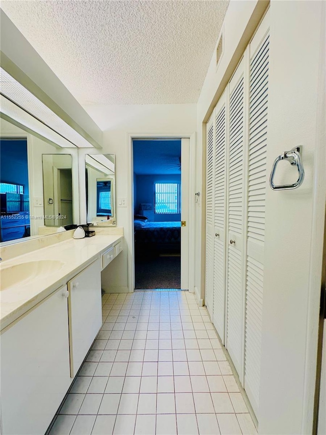 bathroom with tile patterned flooring, vanity, and a textured ceiling