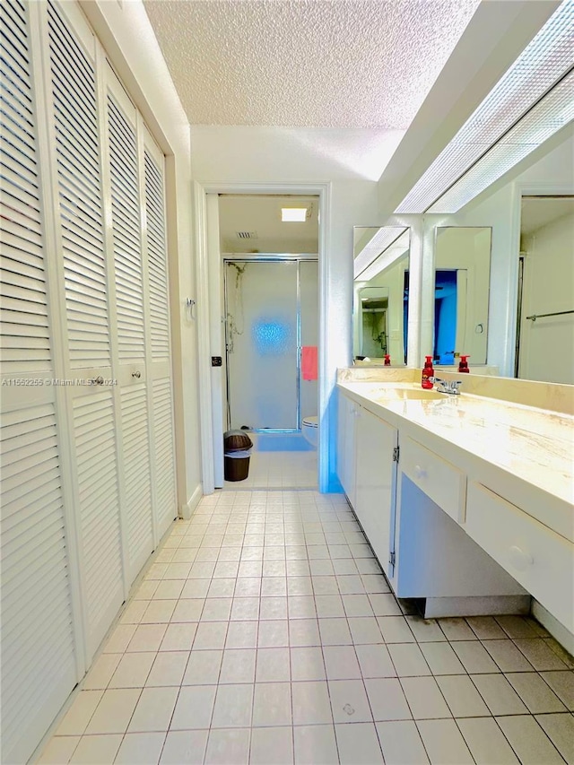 bathroom featuring a textured ceiling, vanity, tile patterned floors, and an enclosed shower