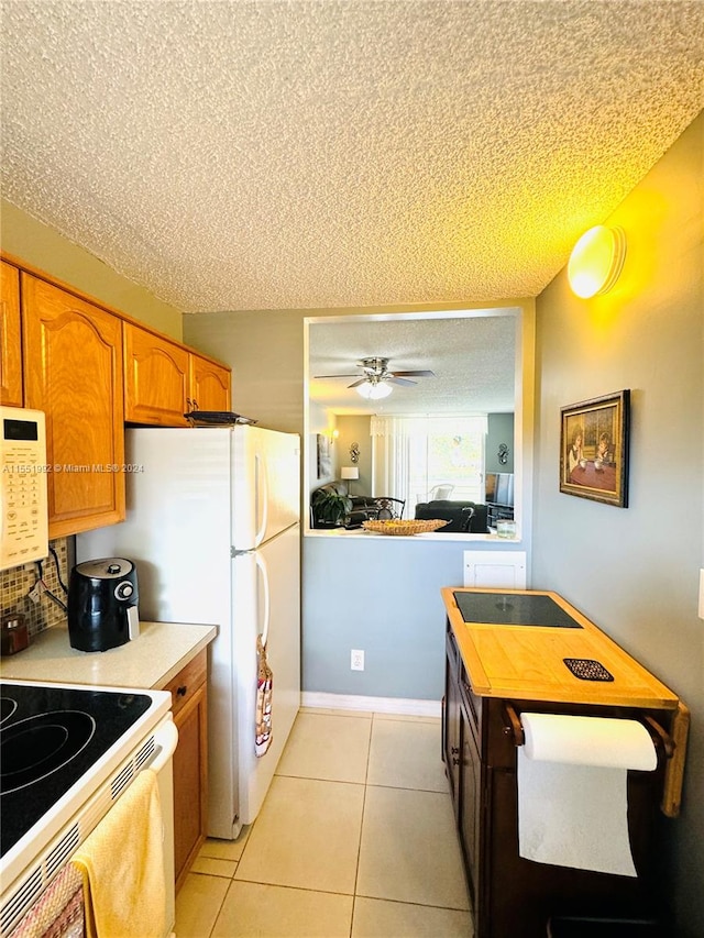 kitchen featuring white appliances, a textured ceiling, light tile flooring, and ceiling fan