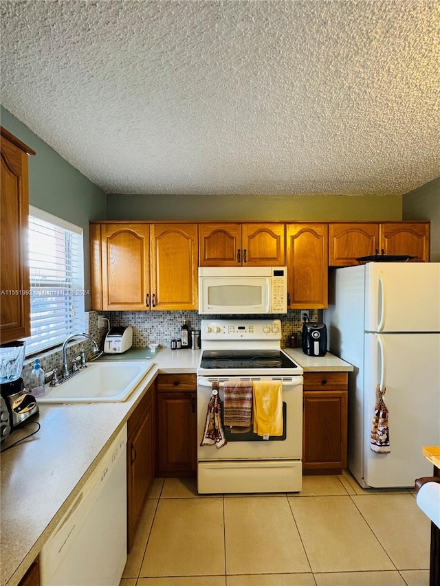 kitchen featuring light tile floors, white appliances, a textured ceiling, and sink