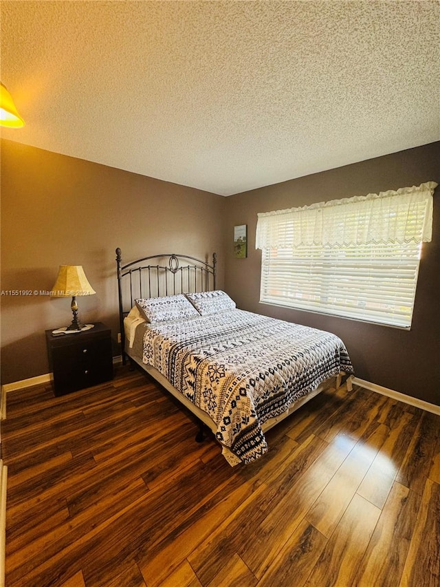 bedroom featuring dark hardwood / wood-style flooring and a textured ceiling