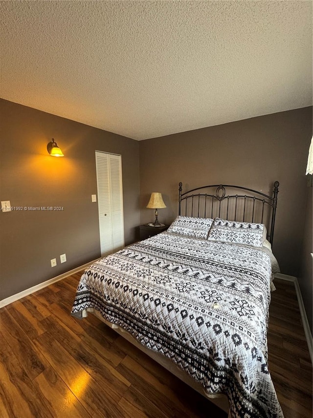 bedroom with a closet, dark wood-type flooring, and a textured ceiling