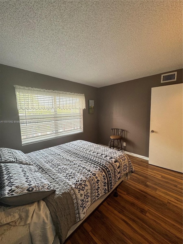 bedroom featuring a textured ceiling and dark wood-type flooring