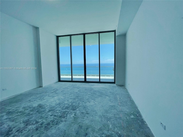 carpeted empty room with a water view and expansive windows