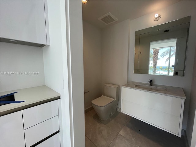 bathroom with toilet, large vanity, and tile floors